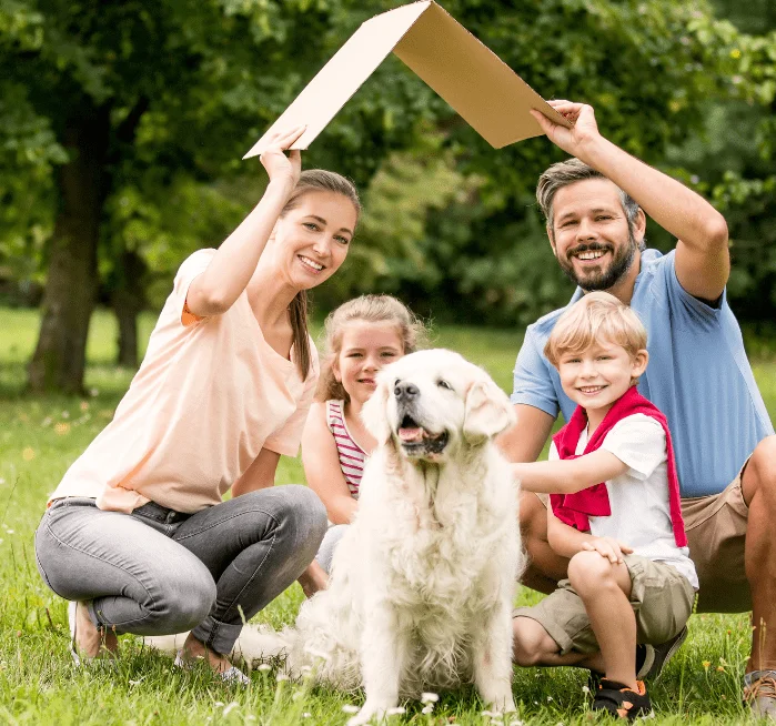 man holding cardboard shaped like roof over his family