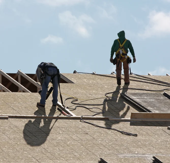 two roofers on a rooftop doing repairs