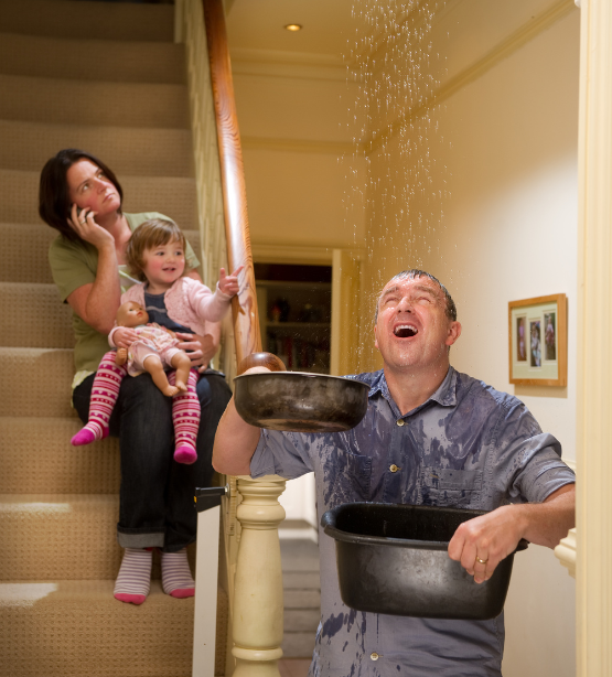 man holding buckets to control leaking roof, woman holding baby and calling roof repair company