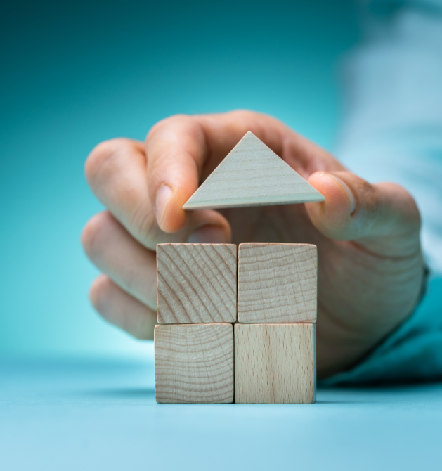 Man holding wooden block roof and about to place on four blocks