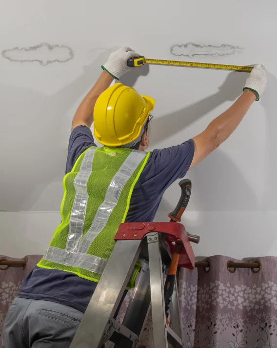 roofer on a ladder checking leak on a roof