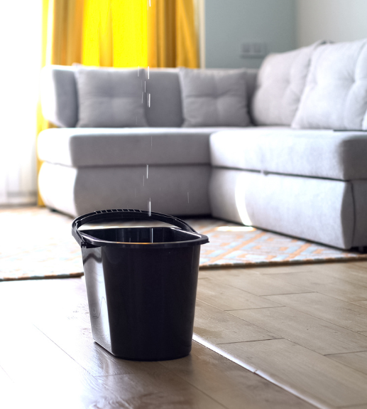  black bucket holding water from a leaking roof indoors